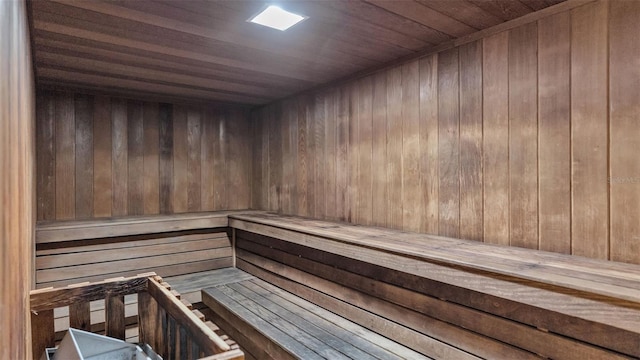 view of sauna featuring wooden ceiling and wooden walls