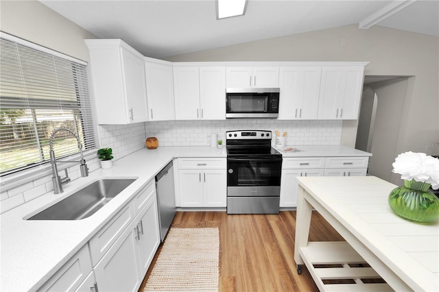 kitchen featuring lofted ceiling with beams, stainless steel appliances, sink, and white cabinets