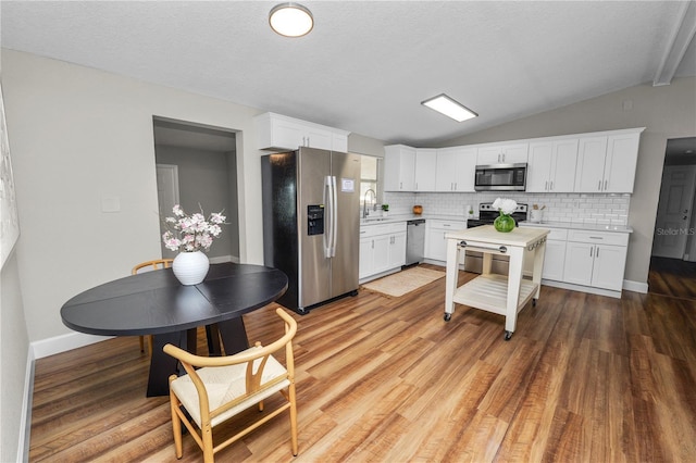 kitchen featuring lofted ceiling, stainless steel appliances, sink, and white cabinets