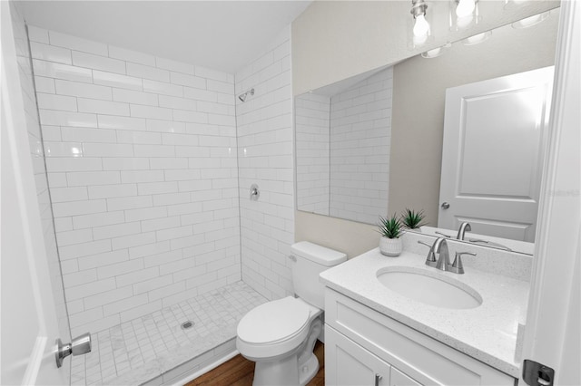 bathroom featuring vanity, a tile shower, and toilet