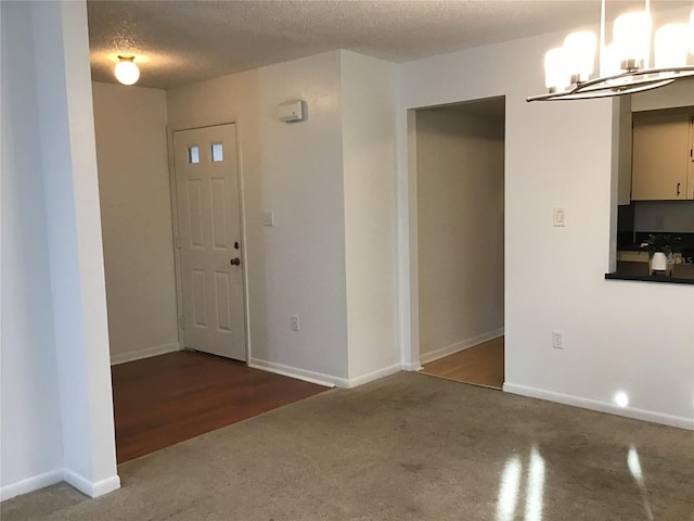 entrance foyer with a notable chandelier, a textured ceiling, and dark hardwood / wood-style flooring