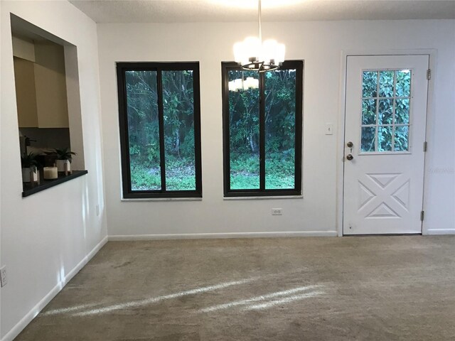 unfurnished dining area with carpet, a notable chandelier, and a healthy amount of sunlight