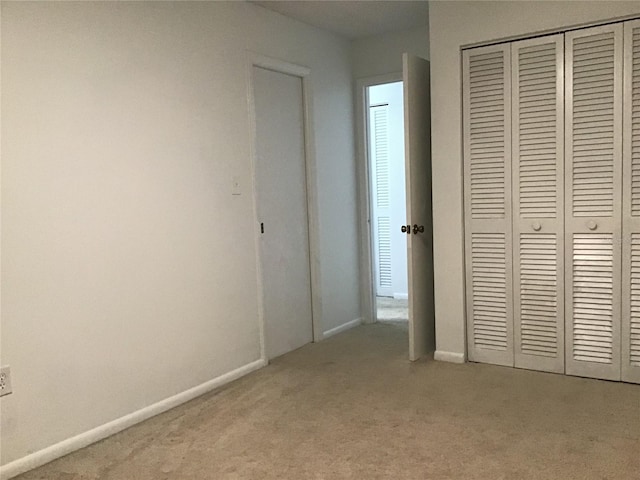 unfurnished bedroom featuring light colored carpet and a closet