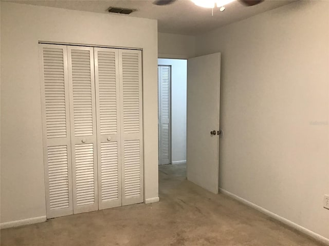 unfurnished bedroom with a closet, light colored carpet, and ceiling fan