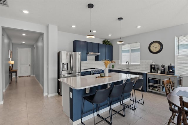 kitchen featuring a breakfast bar area, blue cabinetry, appliances with stainless steel finishes, and a healthy amount of sunlight