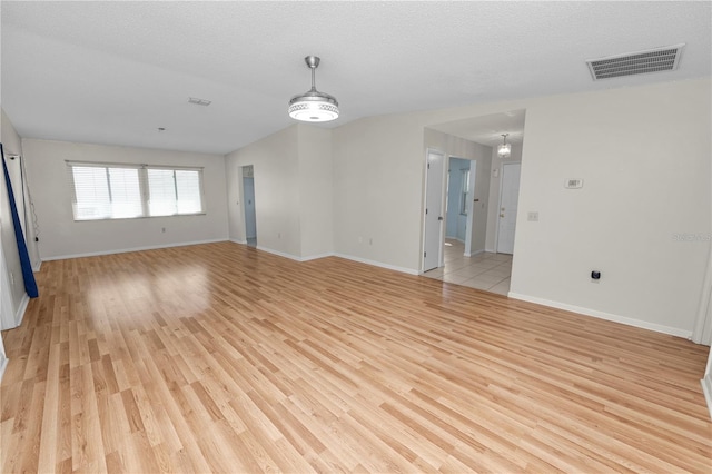 unfurnished room with a notable chandelier, a textured ceiling, and light wood-type flooring