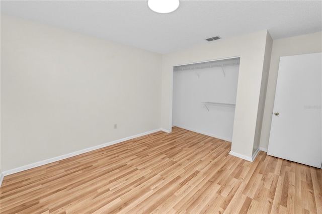 unfurnished bedroom with a closet, a textured ceiling, and light wood-type flooring