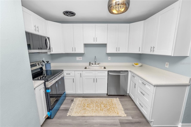 kitchen with light hardwood / wood-style floors, white cabinetry, stainless steel appliances, and sink