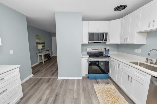 kitchen featuring sink, appliances with stainless steel finishes, light hardwood / wood-style flooring, and white cabinets