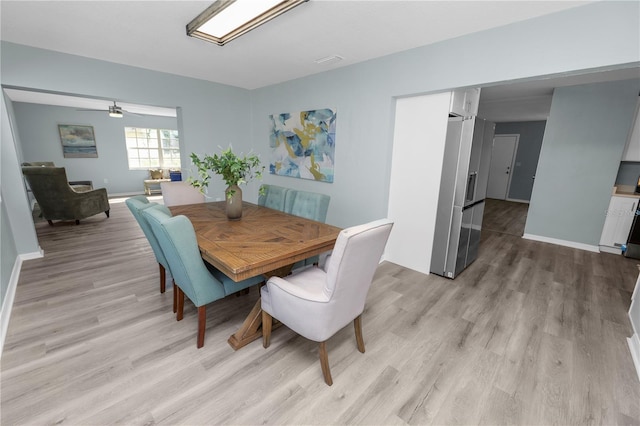 dining space with light hardwood / wood-style floors and ceiling fan