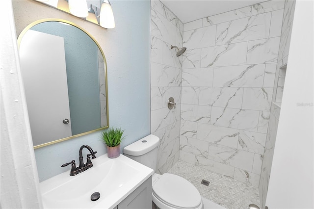 bathroom with vanity, tiled shower, and toilet