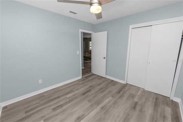 unfurnished bedroom featuring light hardwood / wood-style flooring, a closet, and ceiling fan