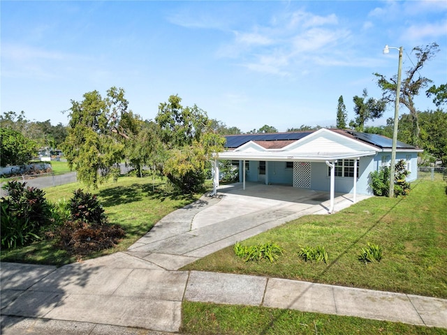 1220 Woodland Ave, Lakeland, FL 33801 - single story home with a front lawn, concrete driveway, an attached carport, roof mounted solar panels, and a metal roof