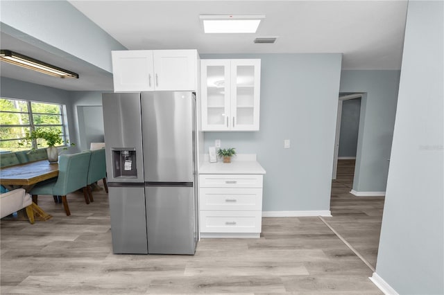 1220 Woodland Ave, Lakeland, FL 33801 - kitchen featuring stainless steel fridge, white cabinets, glass insert cabinets, light wood-style floors, and light countertops