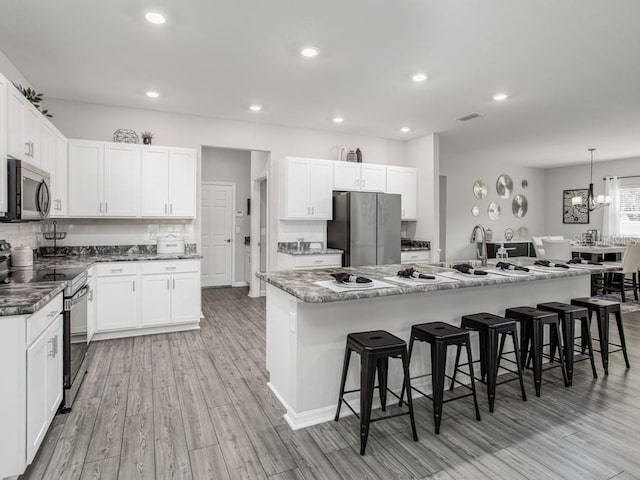 kitchen featuring a large island, light hardwood / wood-style flooring, white cabinetry, and stainless steel appliances