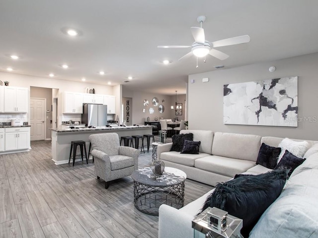 living room featuring light wood-type flooring and ceiling fan