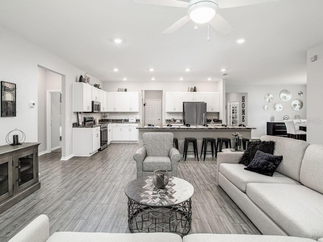 living room featuring light wood-type flooring and ceiling fan