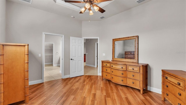 bedroom with a high ceiling, ceiling fan, light hardwood / wood-style flooring, a walk in closet, and a closet