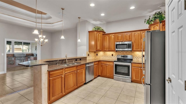 kitchen with stainless steel appliances, kitchen peninsula, ornamental molding, dark stone countertops, and decorative light fixtures