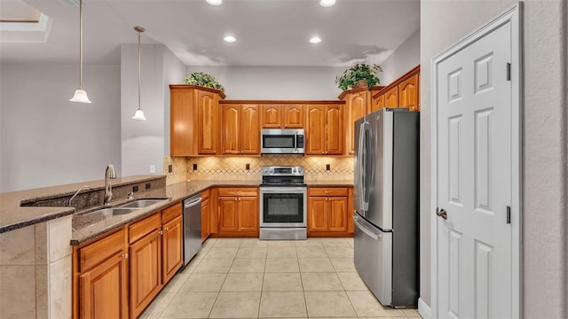 kitchen with dark stone counters, sink, light tile patterned floors, pendant lighting, and appliances with stainless steel finishes