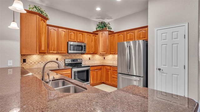 kitchen featuring pendant lighting, appliances with stainless steel finishes, sink, and backsplash