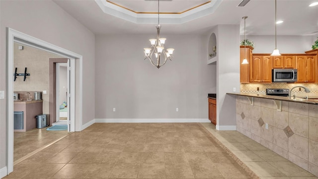 kitchen with an inviting chandelier, decorative backsplash, hanging light fixtures, crown molding, and appliances with stainless steel finishes