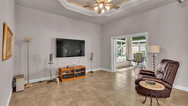 living area featuring crown molding, light tile patterned floors, ceiling fan, and a raised ceiling