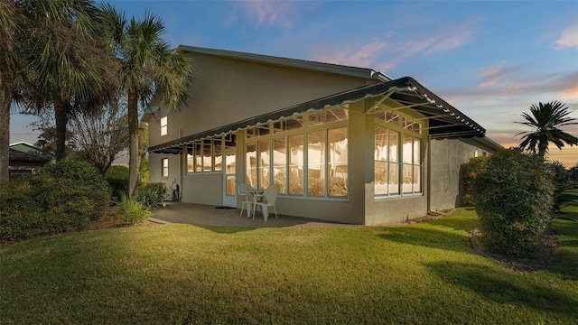 property exterior at dusk featuring a patio and a lawn