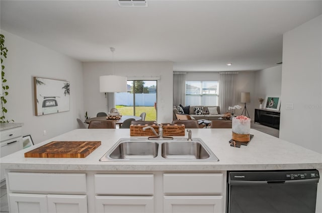 kitchen featuring sink, dishwasher, hanging light fixtures, white cabinets, and a center island with sink