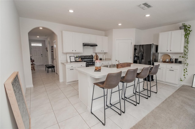 kitchen with black appliances, an island with sink, and white cabinets