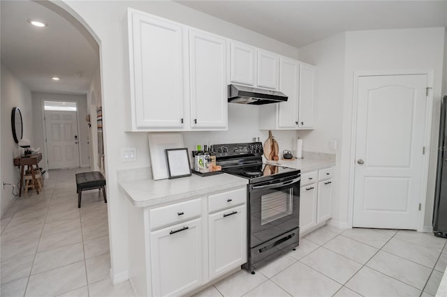 kitchen with stainless steel fridge, white cabinetry, light tile patterned floors, and black electric range