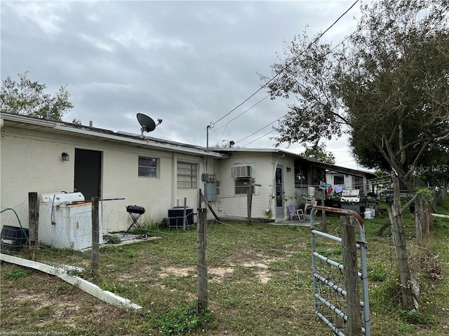 back of house with a lawn and central AC unit