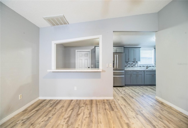 unfurnished living room with light hardwood / wood-style flooring, sink, and lofted ceiling