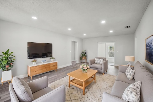 living room featuring a textured ceiling and light wood-type flooring