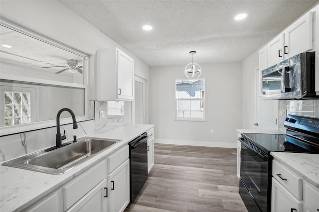 kitchen with white cabinets, hanging light fixtures, black appliances, and sink