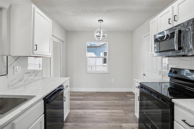 kitchen featuring light hardwood / wood-style floors, white cabinets, black appliances, and pendant lighting