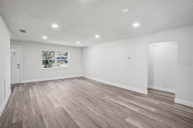 unfurnished room featuring light hardwood / wood-style floors and a textured ceiling