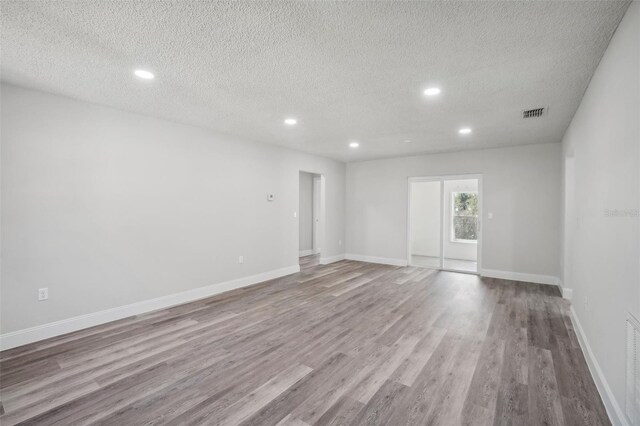 spare room featuring a textured ceiling and light wood-type flooring