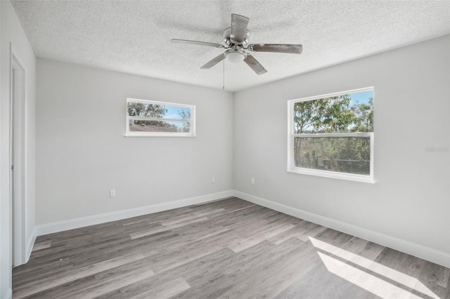 empty room with hardwood / wood-style flooring, a healthy amount of sunlight, and a textured ceiling