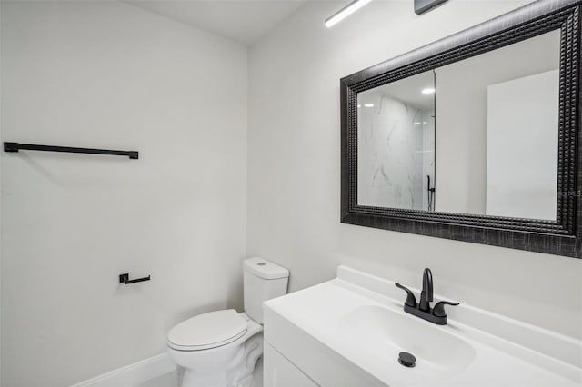 bathroom featuring toilet, vanity, and tiled shower