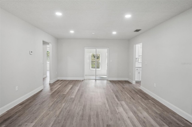 spare room featuring a textured ceiling and hardwood / wood-style flooring