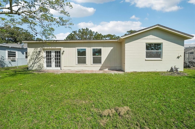 back of property with french doors and a lawn