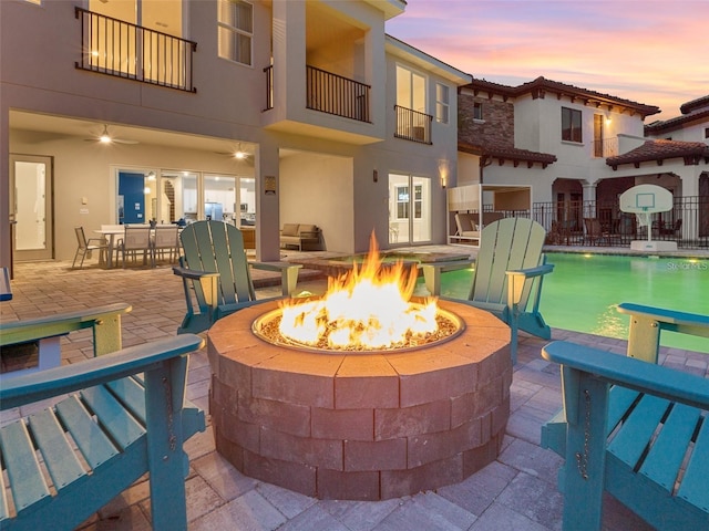 patio terrace at dusk with a fire pit and a balcony