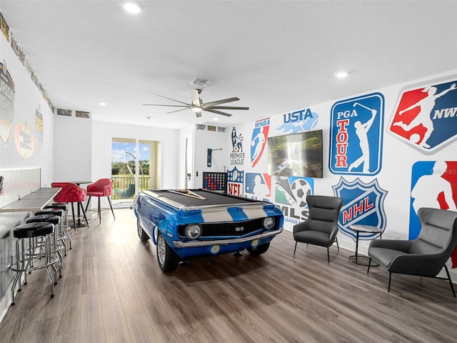 rec room featuring ceiling fan, hardwood / wood-style flooring, and a textured ceiling