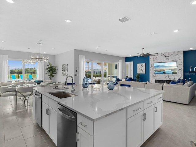 kitchen with a wealth of natural light, sink, white cabinetry, and a center island with sink