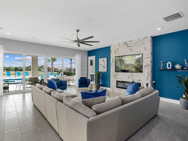 living room featuring ceiling fan, tile patterned floors, a premium fireplace, and a textured ceiling