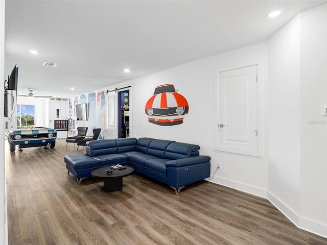 living room with a barn door, hardwood / wood-style flooring, and ceiling fan