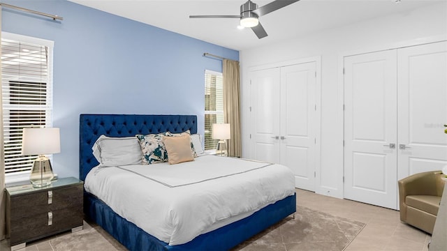 tiled bedroom featuring multiple closets and ceiling fan