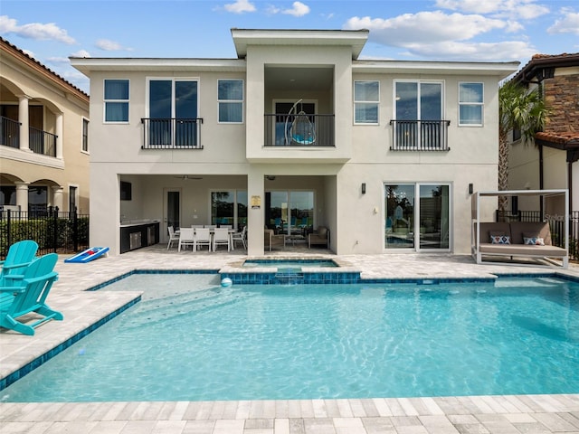 rear view of house with a balcony, a patio area, and a fenced in pool