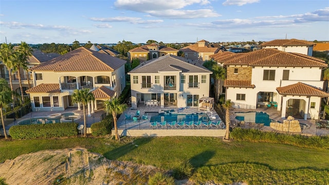 rear view of property featuring a patio area, a lawn, and a balcony